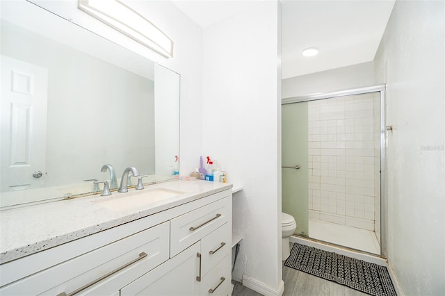 bathroom featuring baseboards, toilet, a shower stall, vanity, and wood finished floors