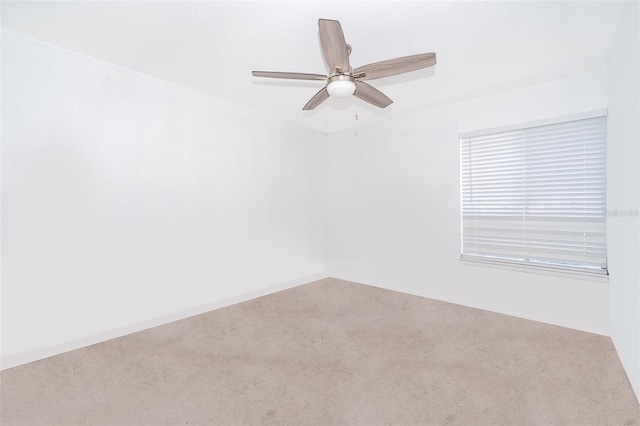 carpeted spare room with baseboards and a ceiling fan