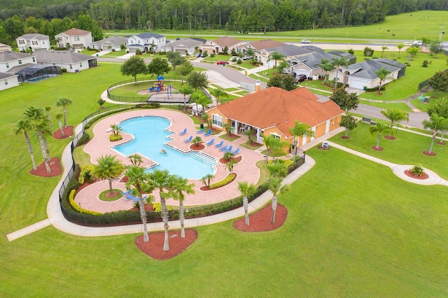 aerial perspective of suburban area featuring a pool and a heavily wooded area