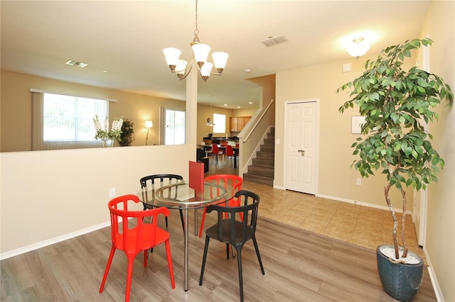dining area featuring wood finished floors, a chandelier, stairs, and baseboards