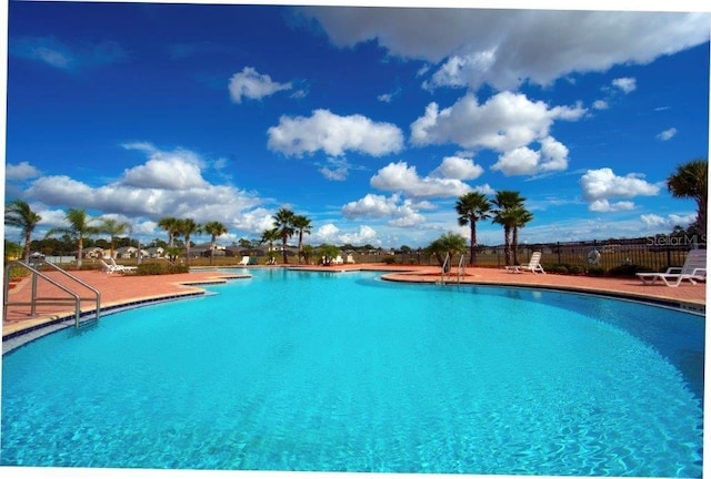 community pool with fence and a patio