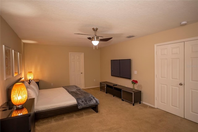 carpeted bedroom with ceiling fan, baseboards, and a textured ceiling