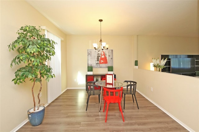 dining space with wood finished floors, a chandelier, and baseboards