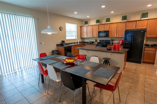 kitchen featuring black appliances, a sink, dark countertops, recessed lighting, and a center island