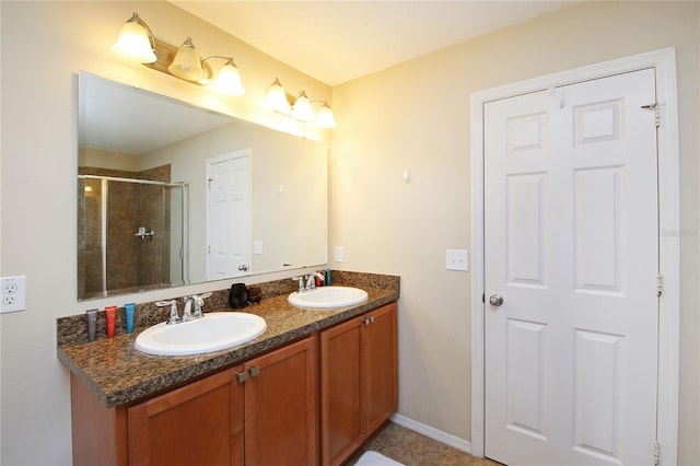 bathroom with a shower stall, double vanity, and baseboards