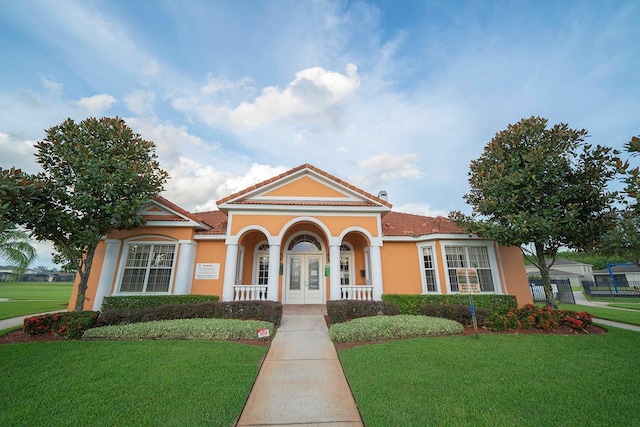mediterranean / spanish-style house with stucco siding, a front lawn, french doors, and a tiled roof