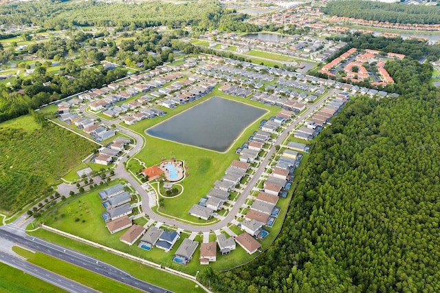 aerial view of property and surrounding area with a nearby body of water, nearby suburban area, and a heavily wooded area