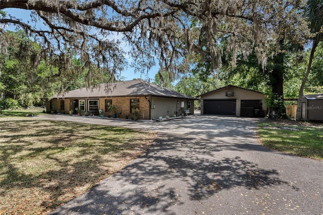 ranch-style house featuring an outbuilding, a garage, and aphalt driveway