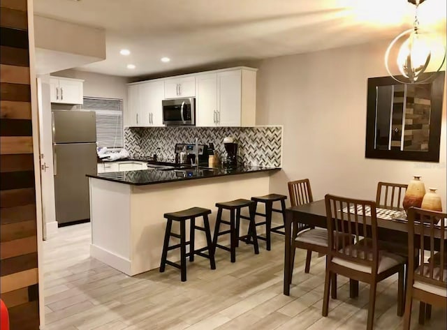 1122 Spaceport Ct, Kissimmee, FL 34741 - kitchen with appliances with stainless steel finishes, a peninsula, dark countertops, light wood-type flooring, and recessed lighting