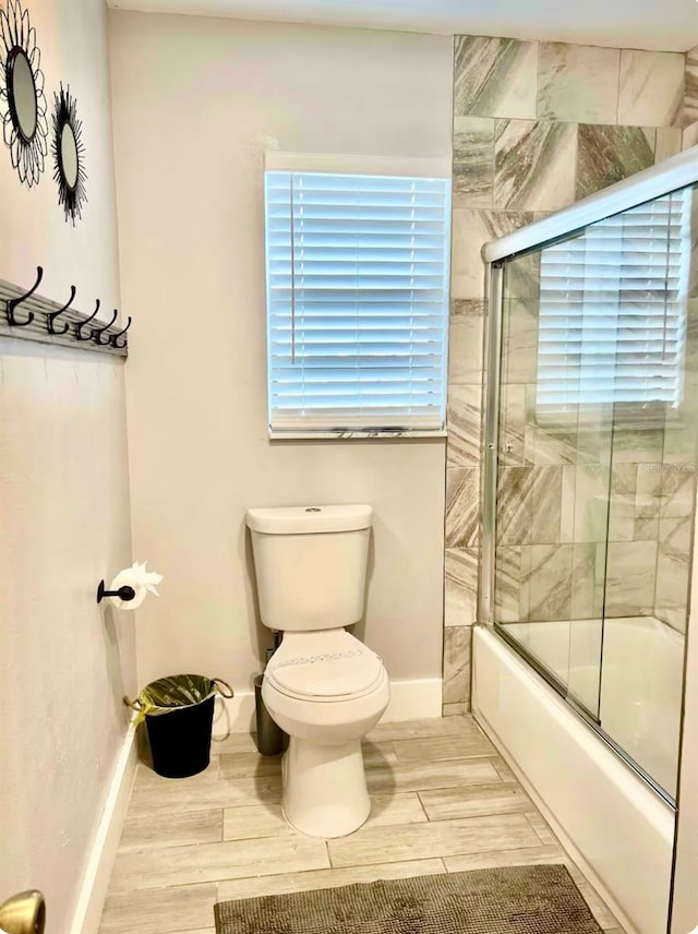 1122 Spaceport Ct, Kissimmee, FL 34741 - full bathroom featuring shower / bath combination with glass door, toilet, baseboards, and wood finished floors