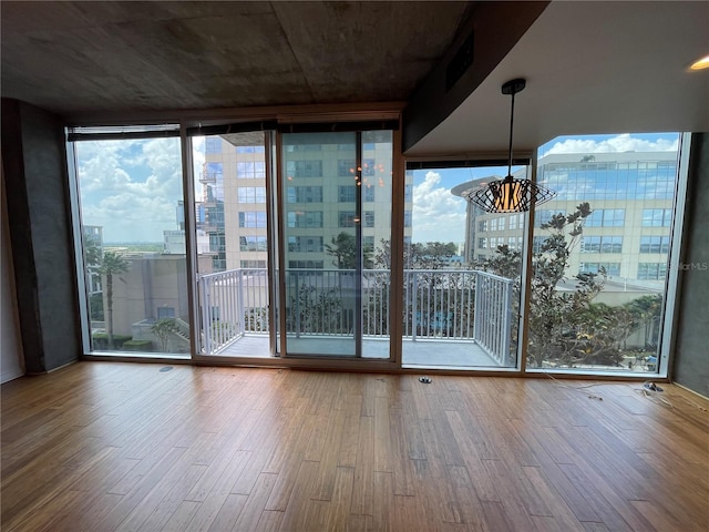 unfurnished room with wood finished floors and a wall of windows