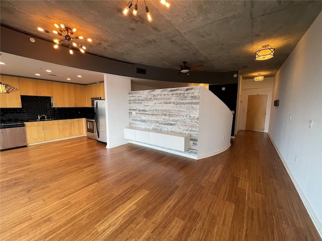 kitchen with light brown cabinets, open floor plan, stainless steel appliances, and wood finished floors