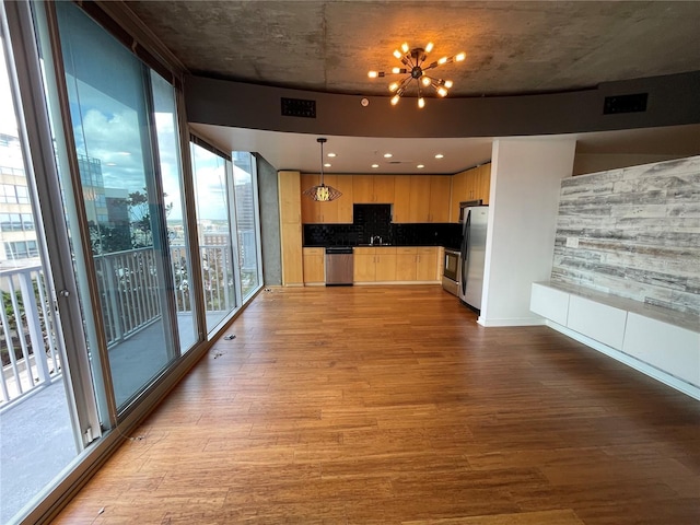 kitchen with a notable chandelier, wood finished floors, light brown cabinets, and stainless steel appliances