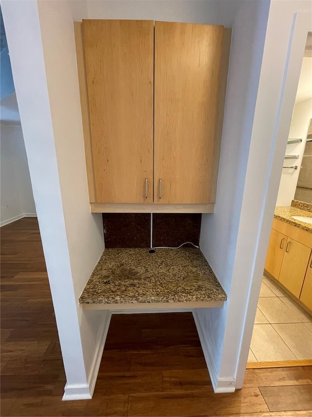 room details featuring a sink, baseboards, and wood finished floors