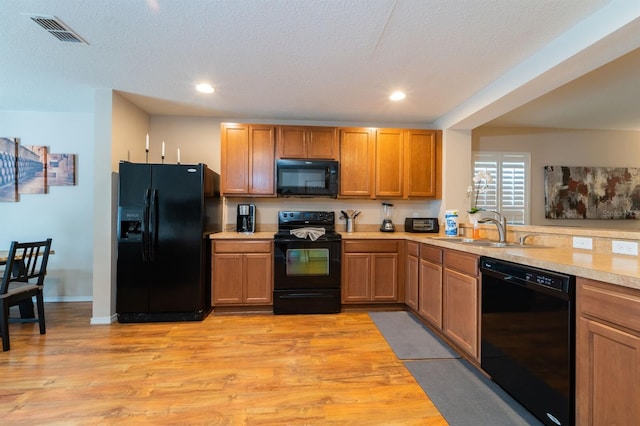 5101 Staniard Dr, Kissimmee, FL 34746 - kitchen with light wood-style flooring, visible vents, black appliances, light countertops, and a sink