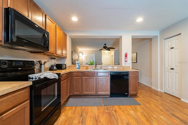 5101 Staniard Dr, Kissimmee, FL 34746 - kitchen featuring light countertops, light wood finished floors, a sink, and black appliances