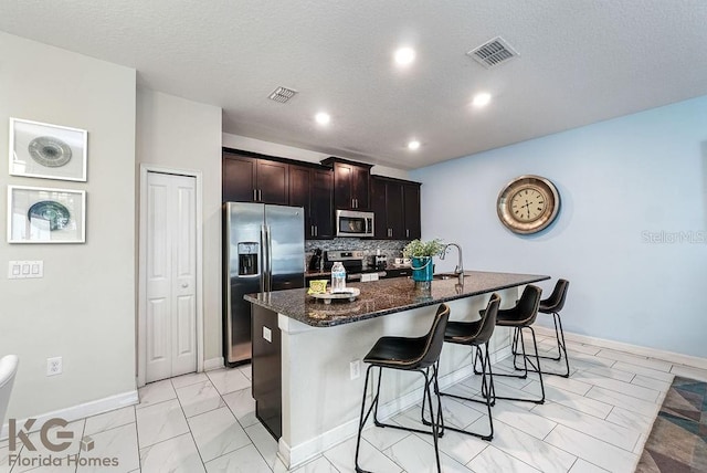 9075 Dogleg Dr, Davenport, FL 33896 - kitchen with appliances with stainless steel finishes, an island with sink, a breakfast bar area, and visible vents