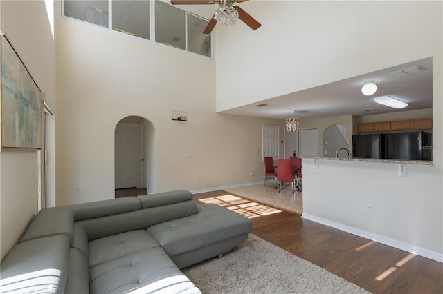 7716 Park Hill Ave, Leesburg, FL 34748 - living room featuring arched walkways, wood finished floors, a ceiling fan, a high ceiling, and baseboards