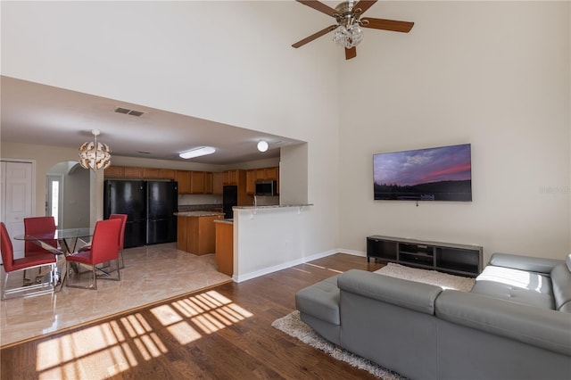7716 Park Hill Ave, Leesburg, FL 34748 - living area with arched walkways, baseboards, light wood finished floors, a ceiling fan, and a high ceiling
