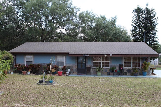 ranch-style house with roof with shingles, stone siding, and a front lawn