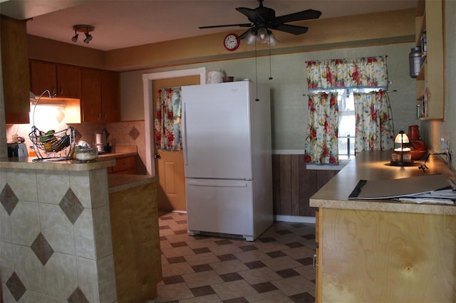 kitchen with light countertops, freestanding refrigerator, ceiling fan, and light floors