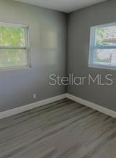 spare room with baseboards, a wealth of natural light, and wood finished floors