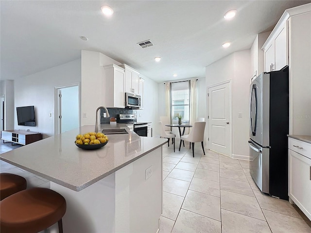 195 Preston Ave, Davenport, FL 33837 - kitchen featuring a sink, stainless steel appliances, a kitchen breakfast bar, visible vents, and white cabinets