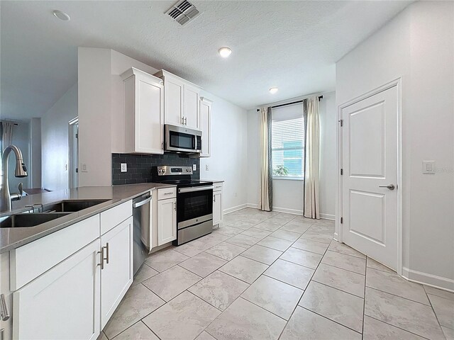 195 Preston Ave, Davenport, FL 33837 - kitchen featuring white cabinetry, decorative backsplash, a sink, visible vents, and stainless steel appliances