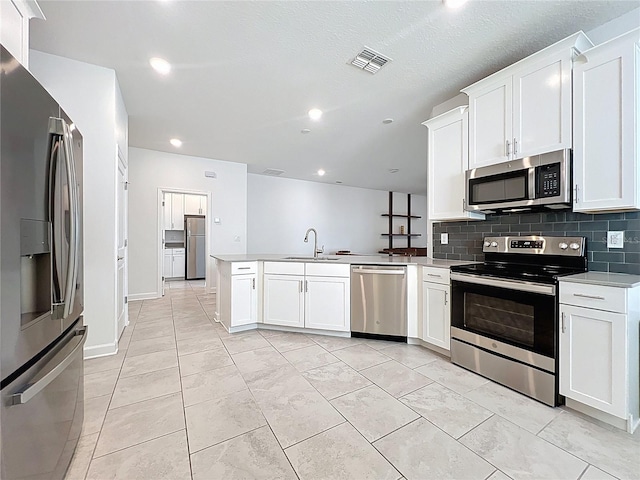 195 Preston Ave, Davenport, FL 33837 - kitchen featuring a sink, a peninsula, stainless steel appliances, and white cabinetry