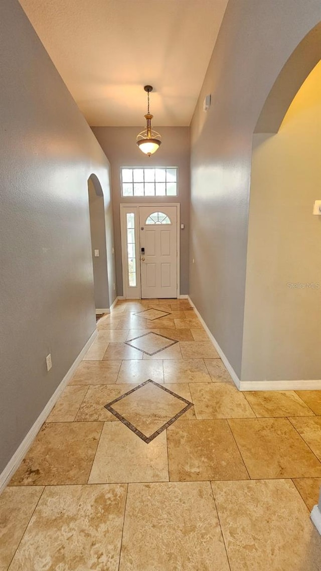 entrance foyer featuring baseboards and arched walkways
