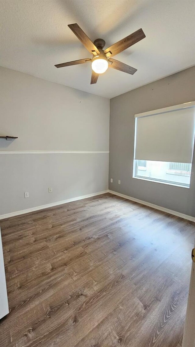 spare room with a textured ceiling, baseboards, wood finished floors, and a ceiling fan