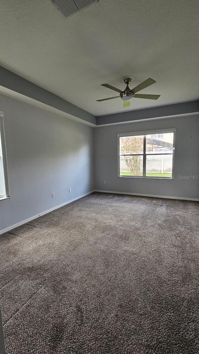 carpeted empty room with baseboards, a textured ceiling, visible vents, and a ceiling fan
