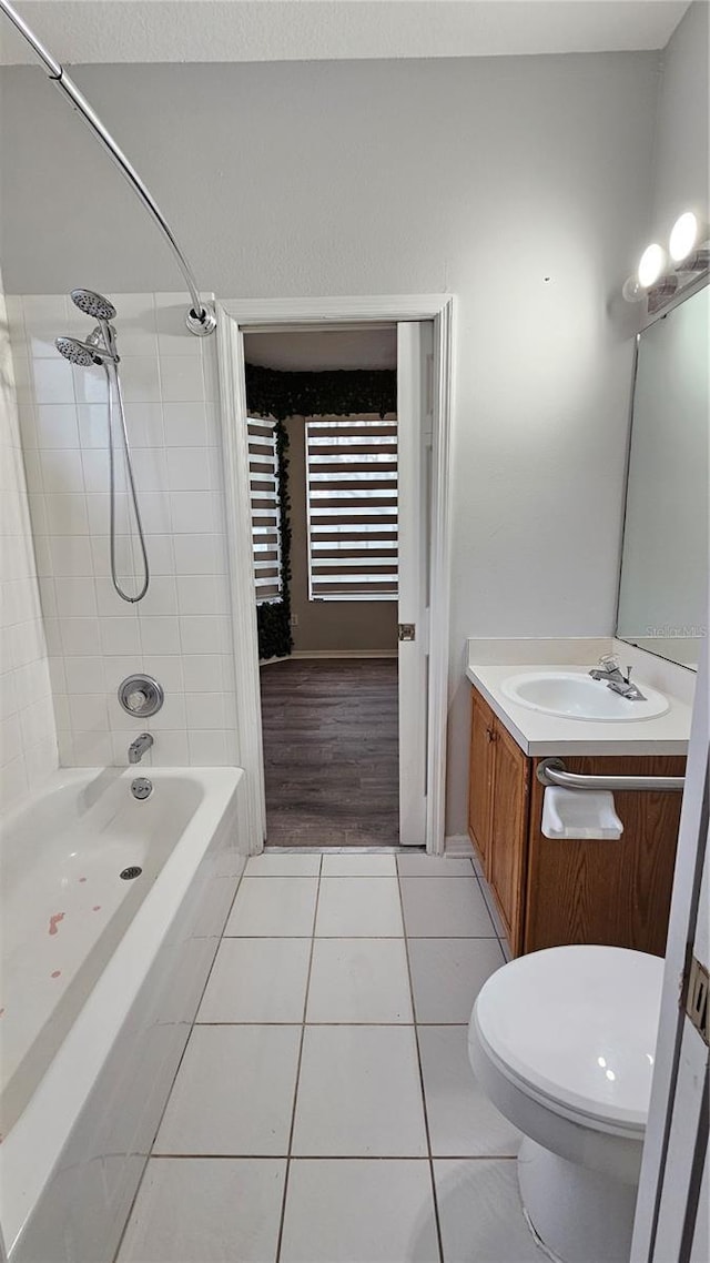 bathroom with toilet, tile patterned flooring, vanity, and  shower combination