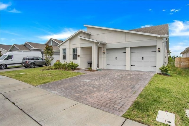view of front facade featuring a garage, stucco siding, decorative driveway, and a front yard
