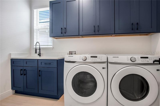 washroom with a sink, baseboards, cabinet space, and washing machine and clothes dryer