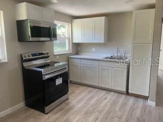 3135 Old Dixie Hwy, Auburndale, FL 33823 - kitchen with light countertops, white cabinets, appliances with stainless steel finishes, and a sink