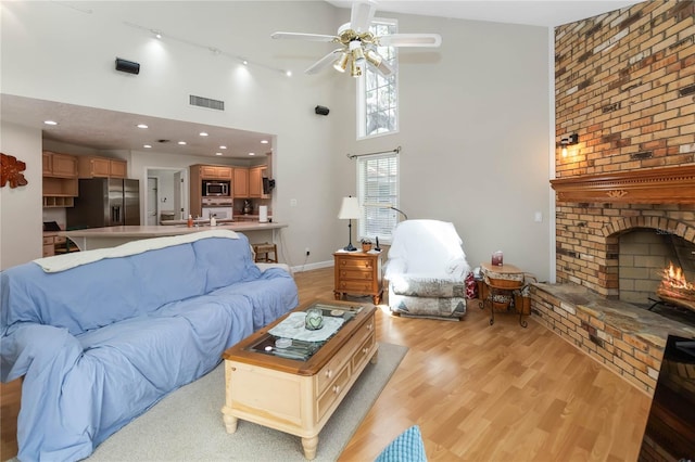 1730 King Henry Dr, Kissimmee, FL 34744 - living room with light wood-style flooring, a brick fireplace, ceiling fan, and visible vents