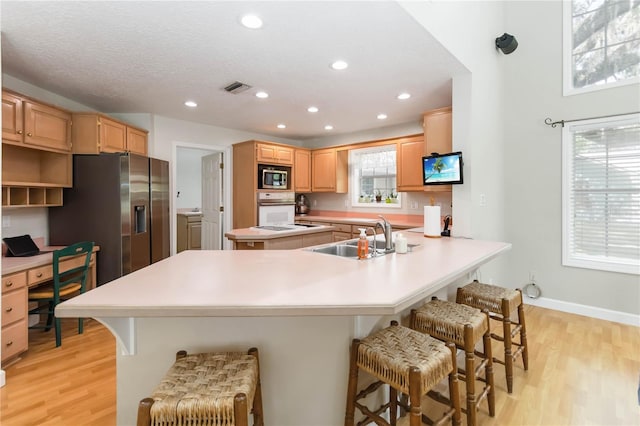 1730 King Henry Dr, Kissimmee, FL 34744 - kitchen featuring light wood-style flooring, a sink, appliances with stainless steel finishes, and a breakfast bar