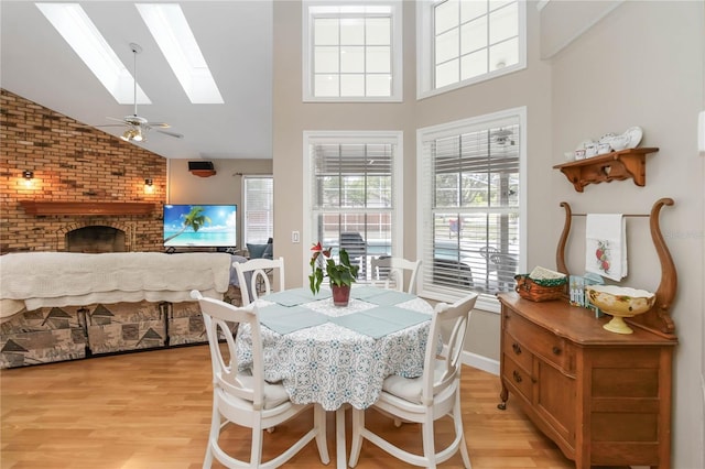 1730 King Henry Dr, Kissimmee, FL 34744 - dining area with high vaulted ceiling, light wood-type flooring, a skylight, and a brick fireplace