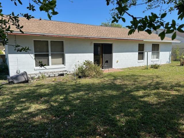133 Bianca Ct, Kissimmee, FL 34758 - back of house with concrete block siding, a shingled roof, and a yard