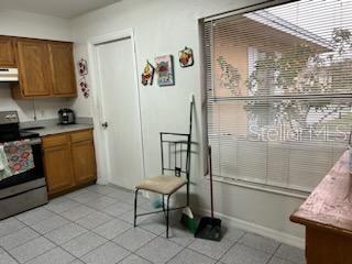 133 Bianca Ct, Kissimmee, FL 34758 - kitchen featuring brown cabinetry, electric range, under cabinet range hood, and light countertops