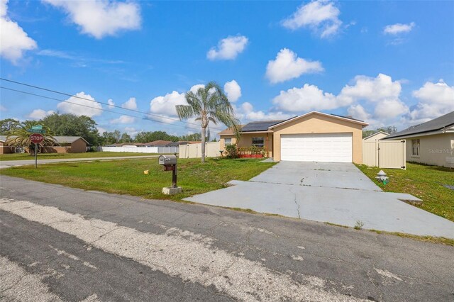 101 Cheltenham Pl, Kissimmee, FL 34758 - ranch-style house with an attached garage, driveway, a gate, a front yard, and solar panels
