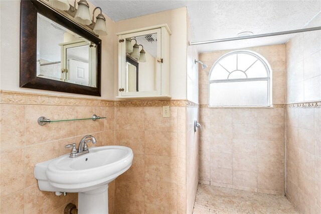 2741 N Poinciana Blvd Unit 49, Kissimmee, FL 34746 - bathroom with wainscoting, tiled shower, tile walls, and a textured ceiling