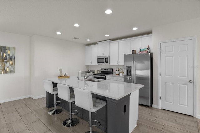 kitchen featuring recessed lighting, a kitchen breakfast bar, stainless steel appliances, light countertops, and white cabinetry