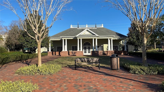 view of front of house with brick siding, french doors, a shingled roof, and stucco siding