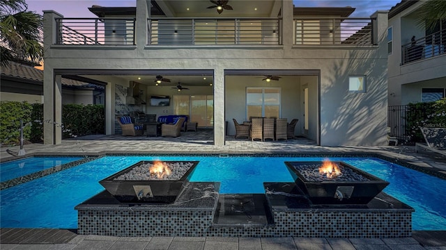 pool at dusk featuring a patio, a ceiling fan, and an outdoor pool