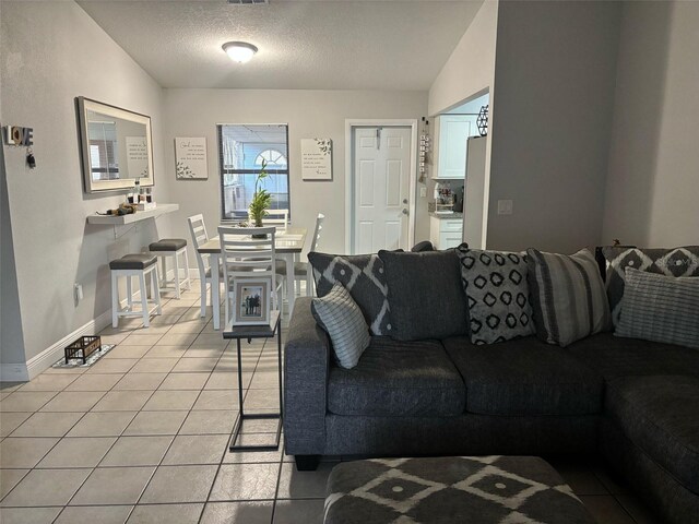 living area with light tile patterned flooring, baseboards, lofted ceiling, and a textured ceiling