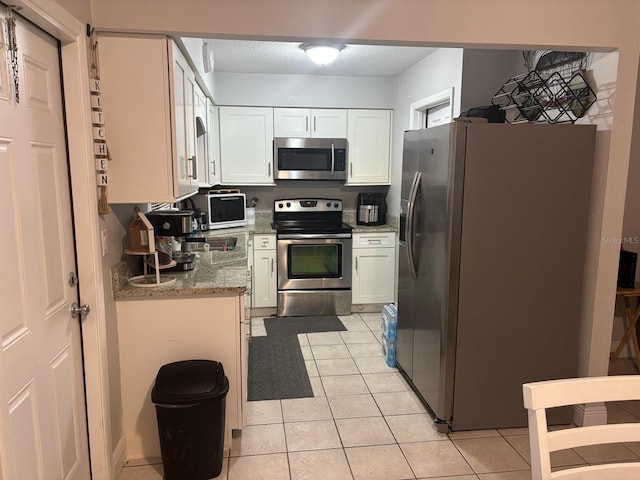 kitchen with light tile patterned flooring, white cabinetry, and appliances with stainless steel finishes