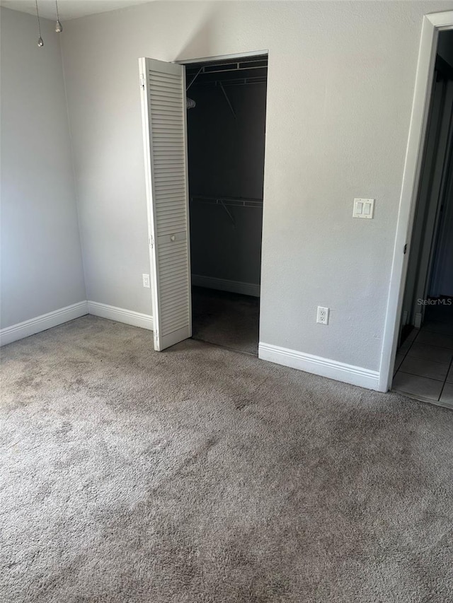 unfurnished bedroom featuring carpet floors, baseboards, and a closet