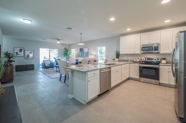 848 San Pedro Ct, Kissimmee, FL 34758 - kitchen with open floor plan, a peninsula, visible vents, stainless steel appliances, and a sink